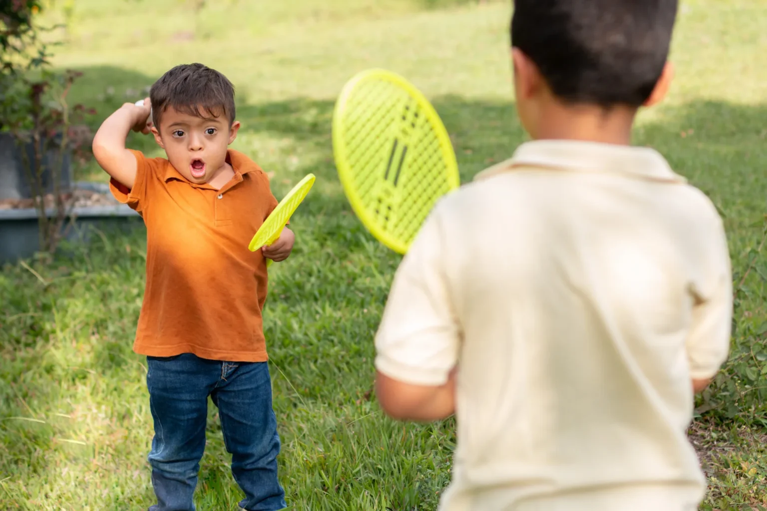 criança feliz com síndrome de down a jogar ténis