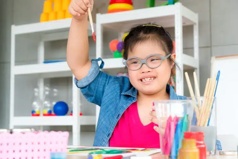 criança com autismo e complexo de deficiência genética a pintar